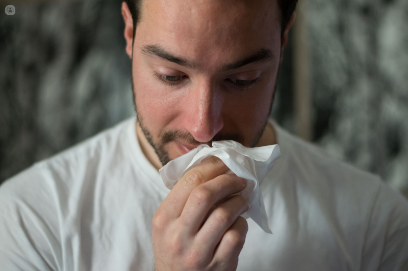 Man blowing his nose. Having a blocked or runny nose is a common symptom of the common cold.